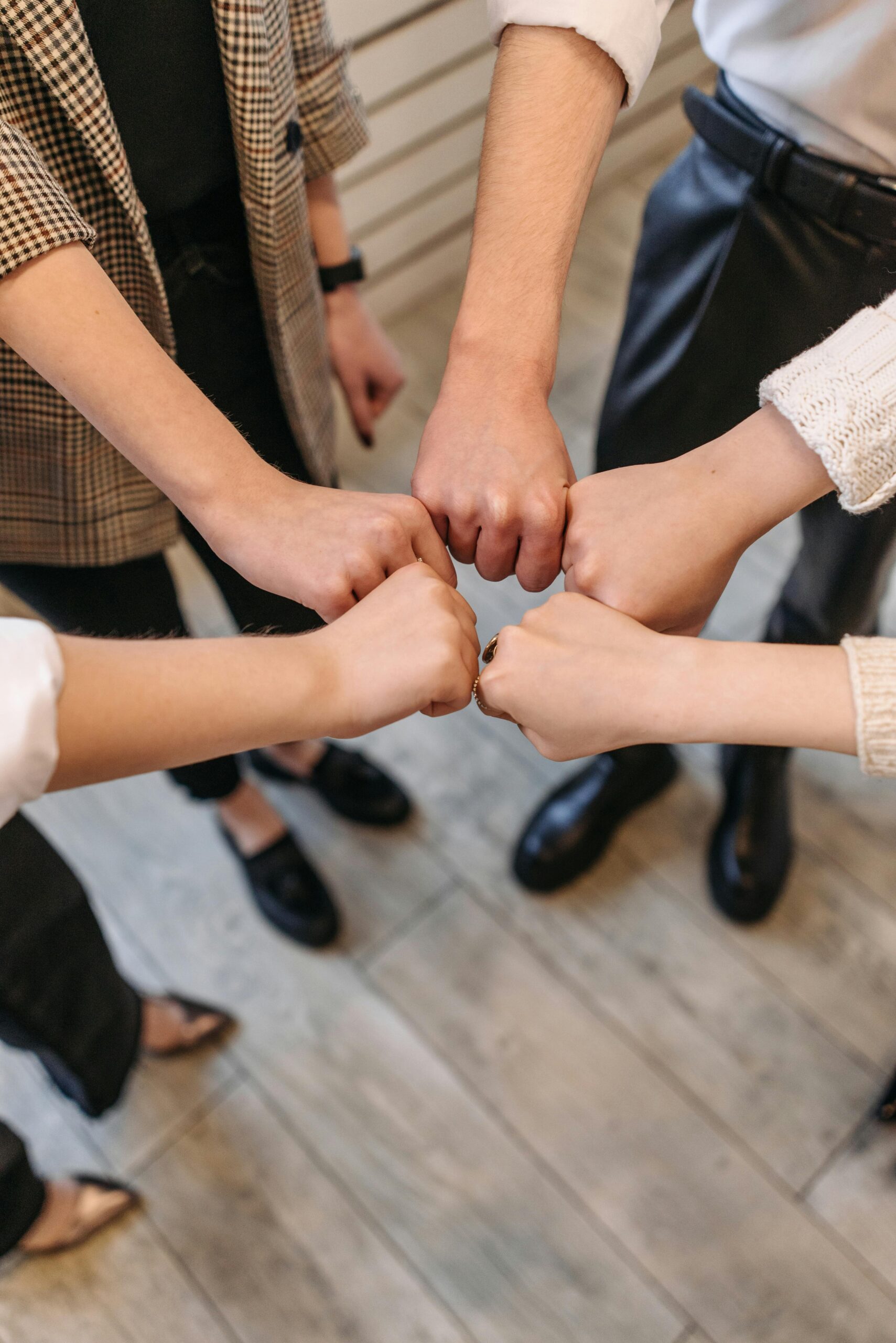 About a group of people standing in a circle touching fists together during a team activity