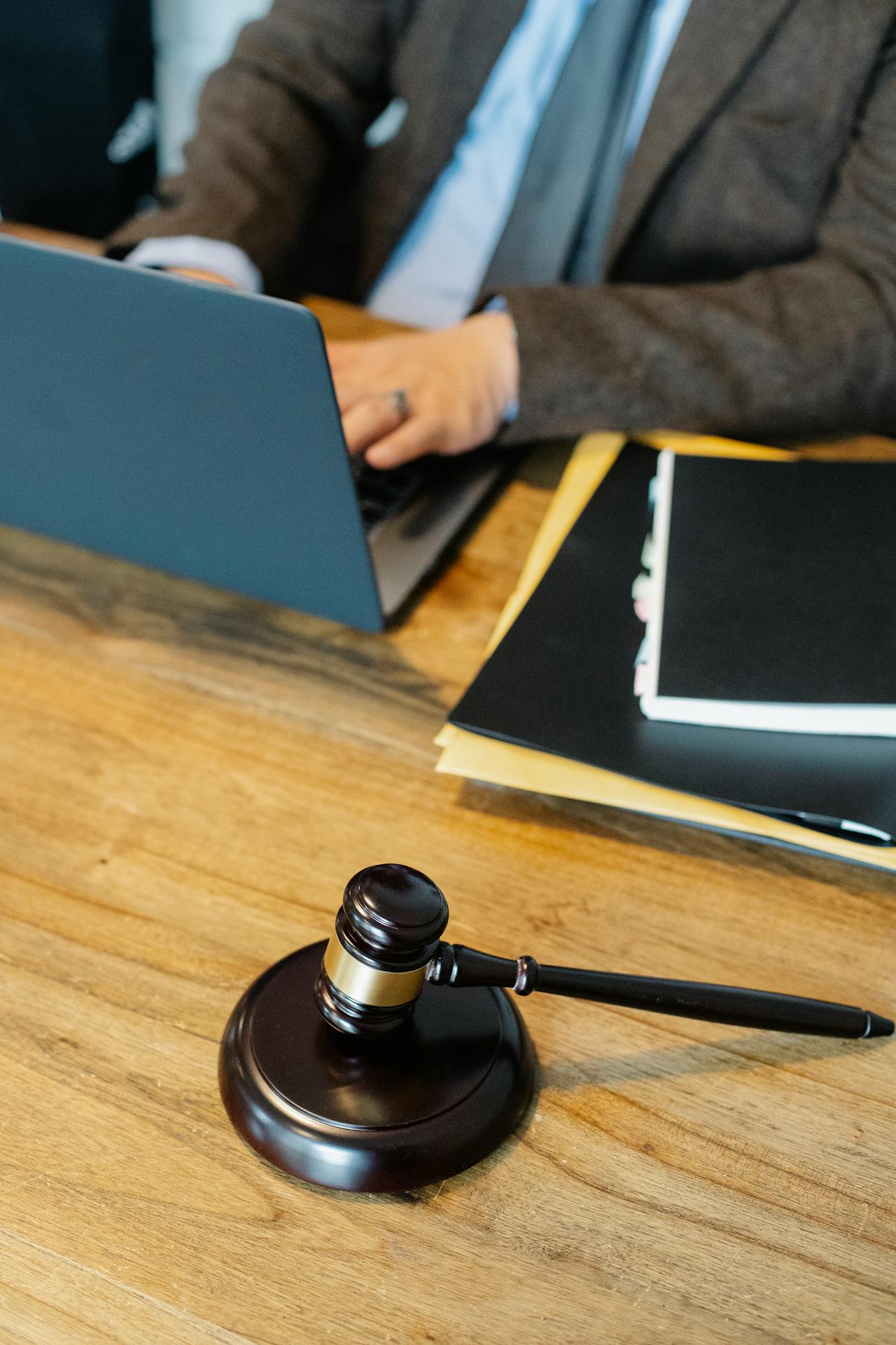Judge’s gavel resting on a wooden desk beside an open laptop and legal files at a law firm
